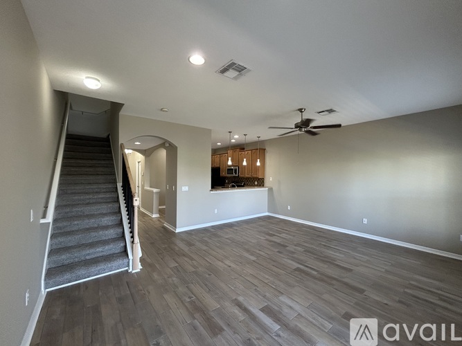 A spacious room with a staircase and a ceiling fan.