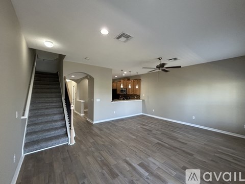 A spacious room with a staircase and a ceiling fan.