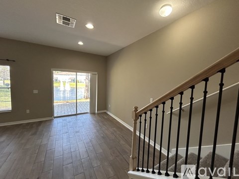 A room with a staircase and a sliding glass door.