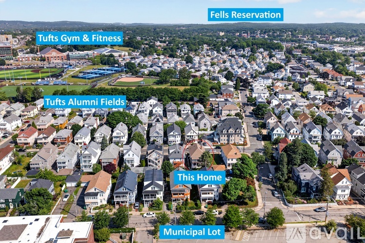 An aerial view of a neighborhood with labeled areas such as Tufts Gym & Fitness, Tufts Alumni Fields, This Home, Municipal Lot, Fells Reservation, and Tufts Gym &