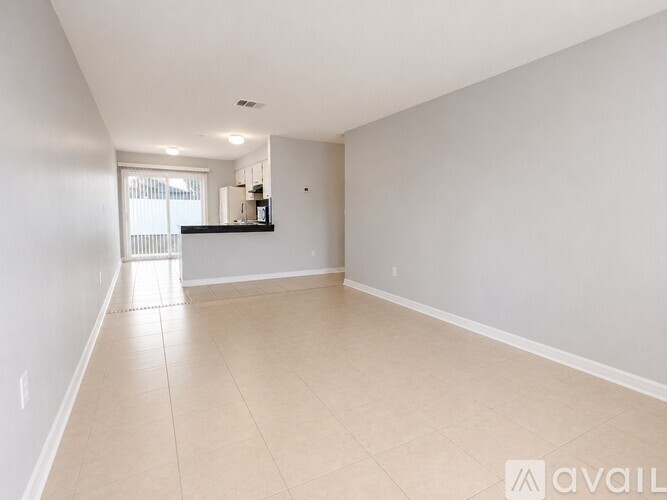 A spacious room with beige tiled flooring and white walls.