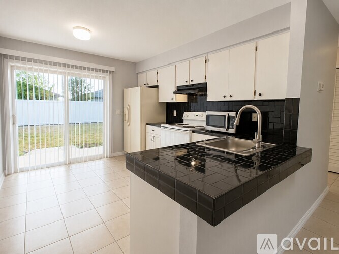 A kitchen with black countertops and white cabinets.