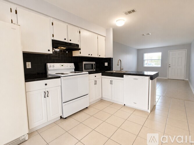 A kitchen with white cabinets and black countertops.