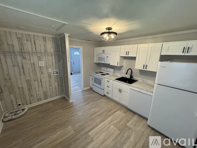 A kitchen with white appliances and wooden floors.