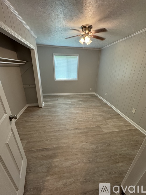 A room with a ceiling fan and a door on the left.