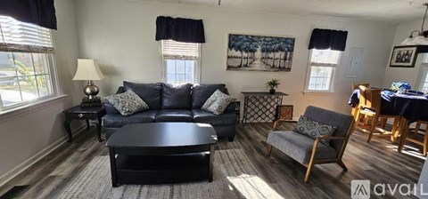 A living room with a black couch and a wooden coffee table.
