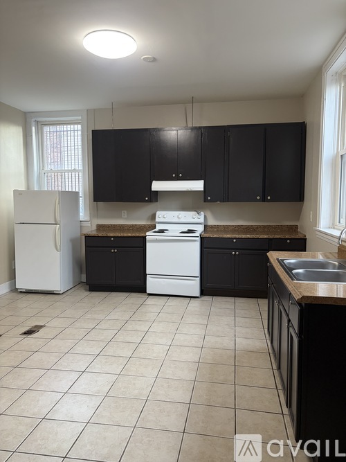 A kitchen with black cabinets and a white fridge.
