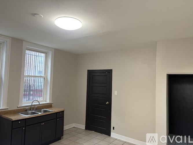 A kitchen with black cabinets and a black door.