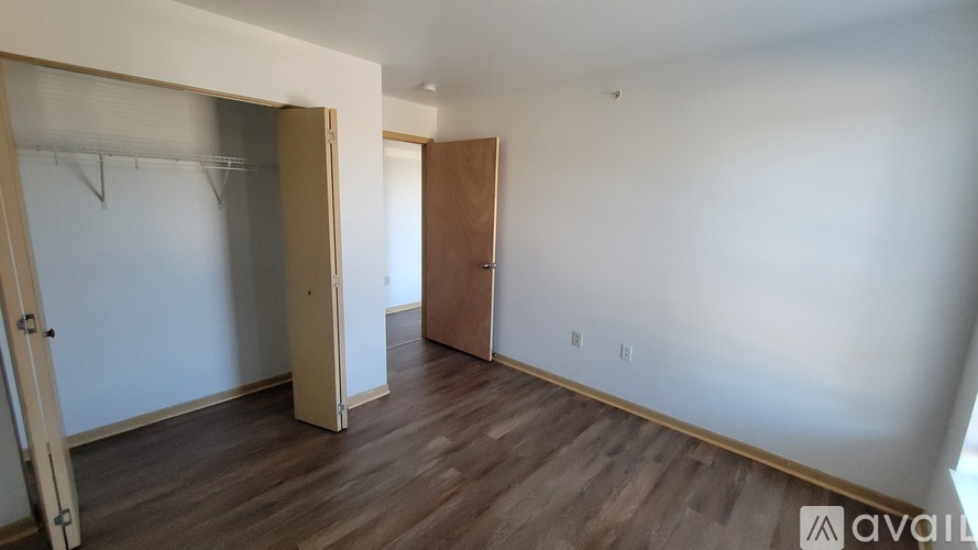 A room with a wooden floor and a white wall with a door and a wardrobe.