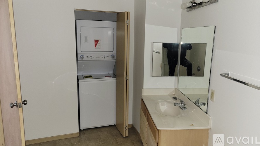 A bathroom with a sink, mirror, and a washer and dryer.