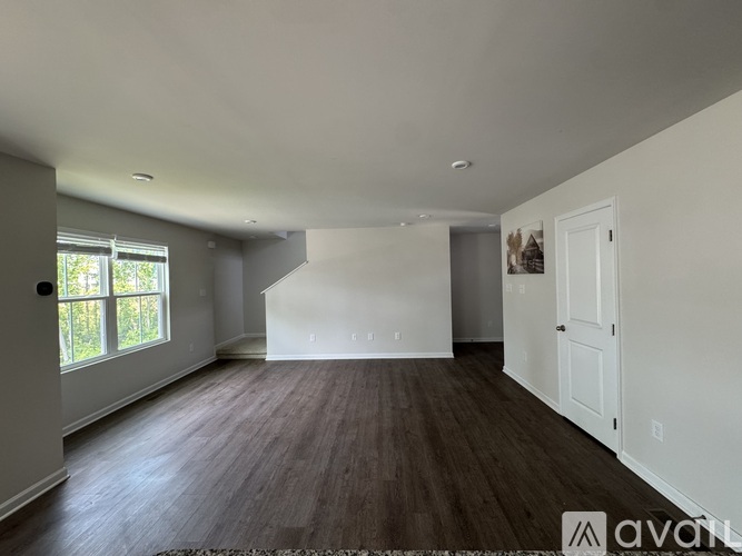 A spacious room with wooden floors and white walls.