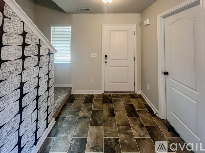 A hallway with a tiled floor and a white door.