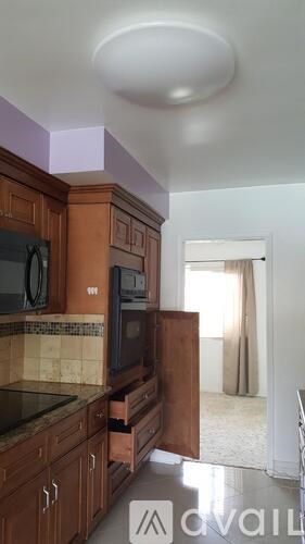 A kitchen with wooden cabinets and a black microwave.