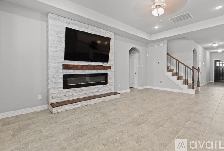 A spacious living room with a fireplace and a staircase.