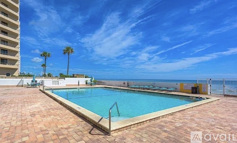 A swimming pool surrounded by a brick patio and palm trees.