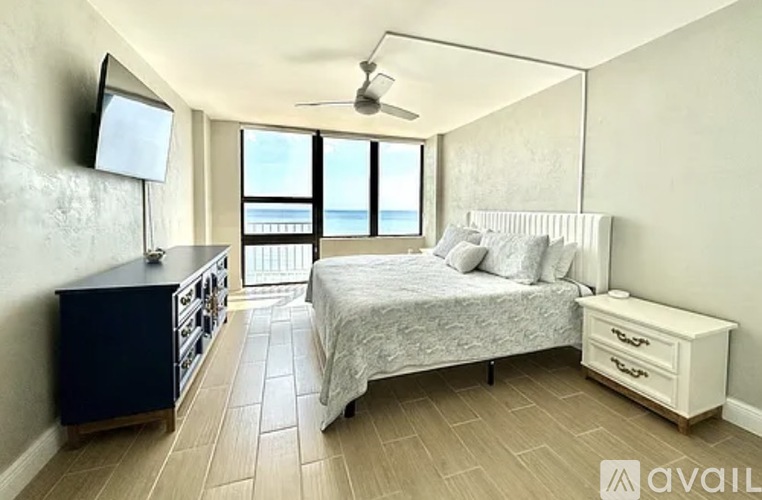 A bedroom with a large bed, a dresser, and a television.