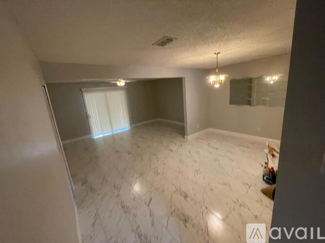 A spacious room with marble flooring and a window with blinds.