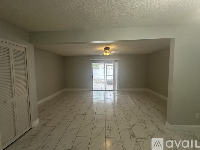 A spacious room with a marble floor and a chandelier.