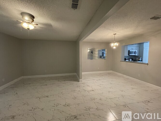 A spacious room with a marble floor and a chandelier.