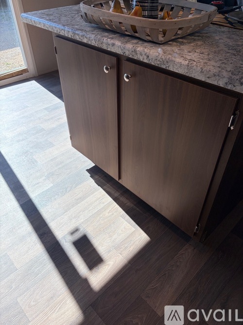 A kitchen with a wooden floor and a counter with a basket on it.