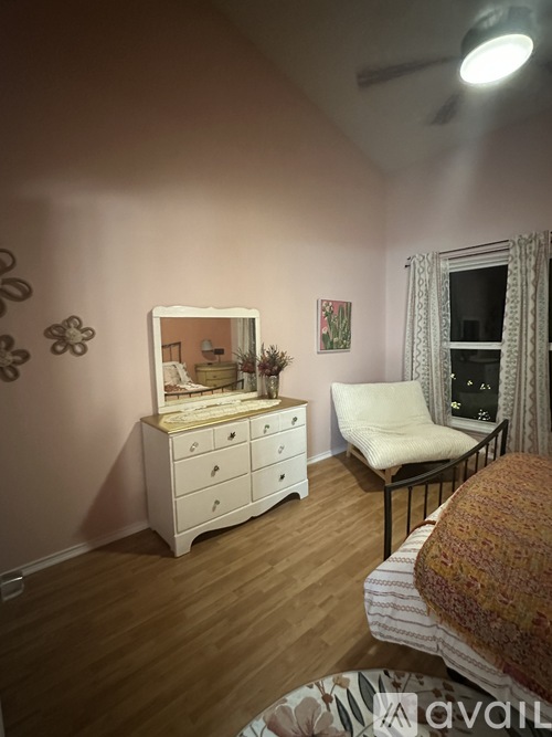 A bedroom with a white dresser and a chair.