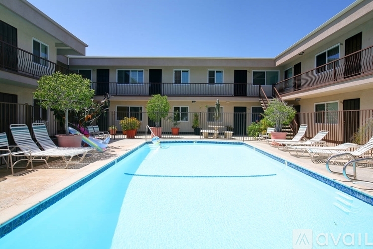 A pool in front of apartment buildings with chairs around it.