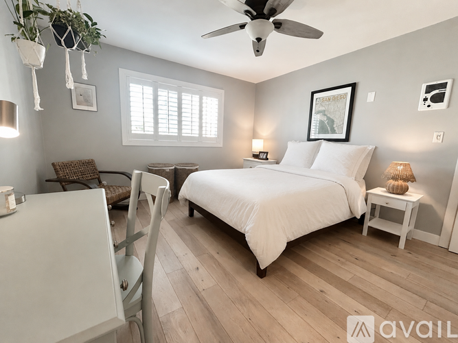 A bedroom with a bed, chair, and ceiling fan.