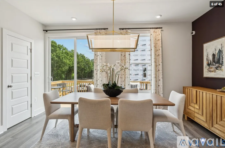 A dining room with a table and chairs and a view of the outside.