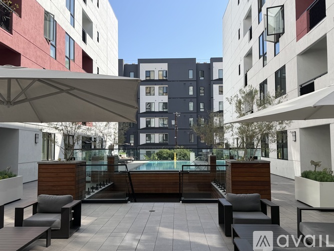 A modern outdoor seating area with benches and a table is surrounded by contemporary buildings.