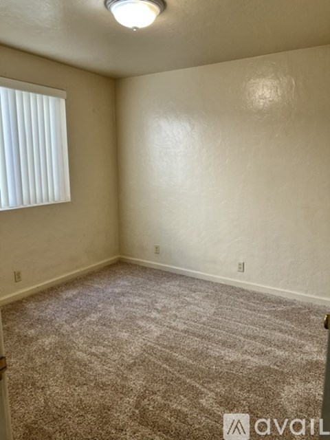 A room with a carpeted floor and a window with blinds.