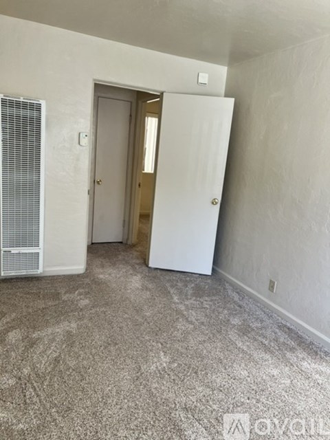 A room with a carpeted floor, a door, and a window with blinds.