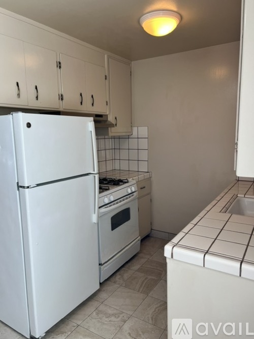 A white refrigerator and oven in a kitchen with white cabinets.