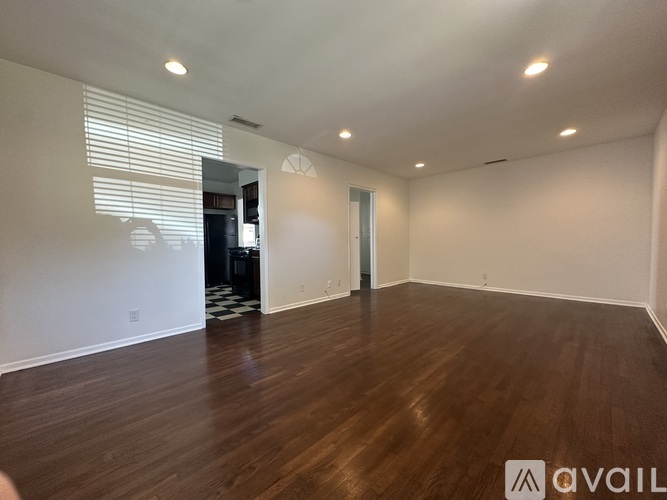 A room with wooden floors and a doorway leading to another room.