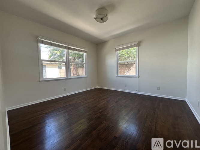 A room with wooden floors and two windows.