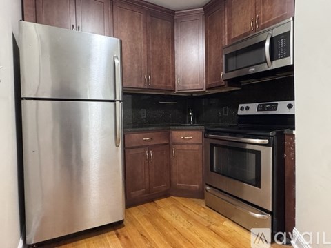 A kitchen with a stainless steel refrigerator, microwave, oven, and wooden cabinets.