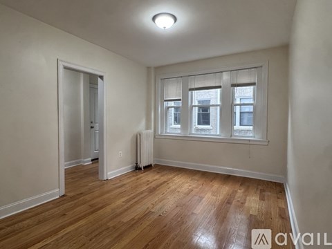 A room with wooden floors and a window with blinds.