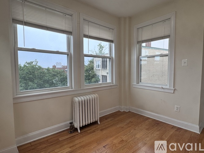 A room with a white radiator and wooden flooring.