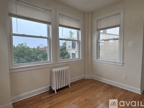 A room with a white radiator and wooden flooring.
