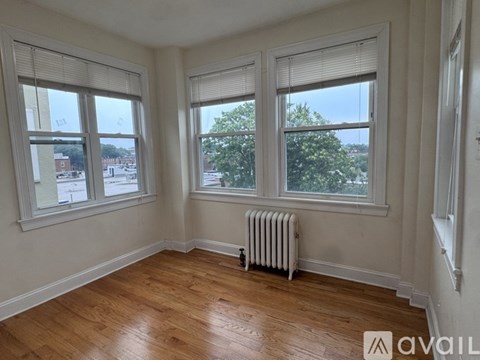 A room with two windows and a radiator on the floor.