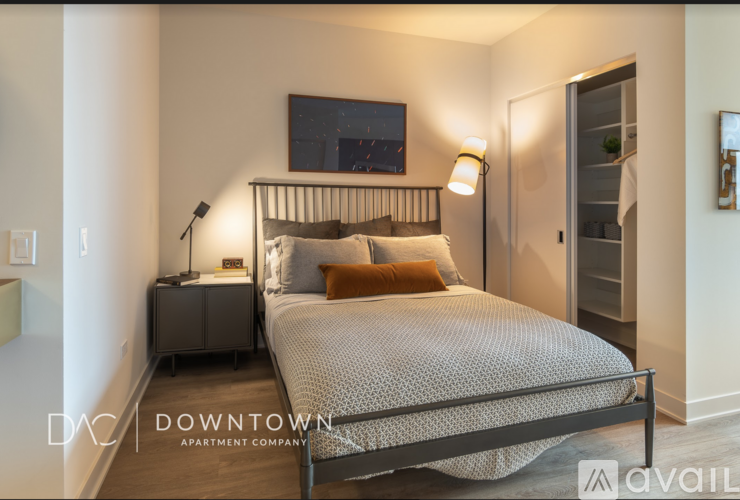 A bedroom with a bed, nightstand, and a painting on the wall.