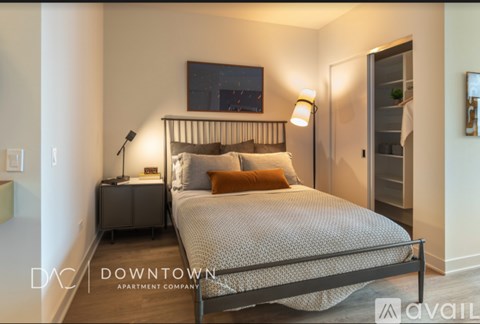 A bedroom with a bed, nightstand, and a painting on the wall.