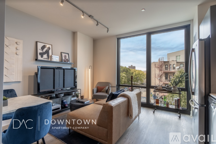 A living room with a television, a couch, and a large window overlooking a cityscape.