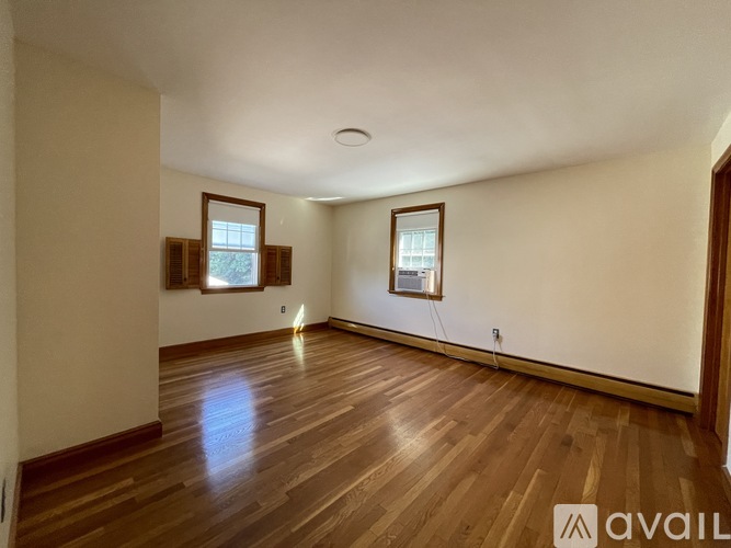 A room with wooden floors and two windows.