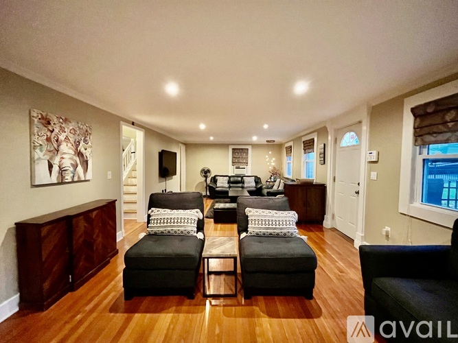 A living room with a black couch and a wooden floor.
