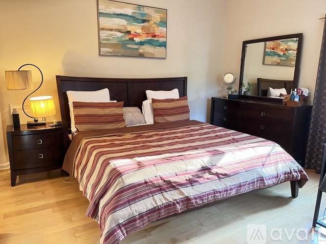A bedroom with a large bed and a painting on the wall.