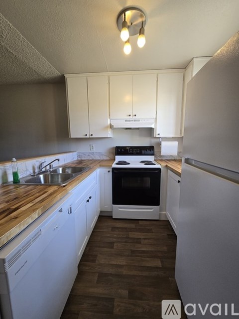 A kitchen with white cabinets and a wooden counter top.