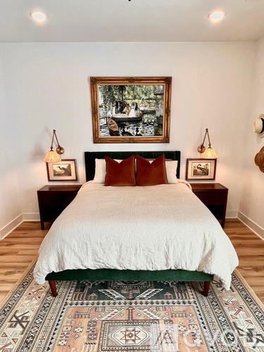 A bedroom with a large bed and a framed picture on the wall.