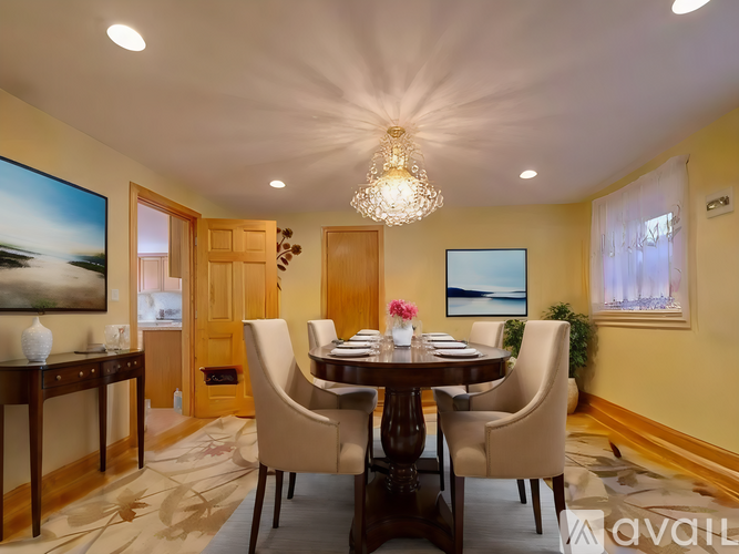 A dining room with a table set for six and a chandelier hanging from the ceiling.