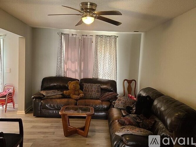 A living room with a brown leather couch and a ceiling fan.