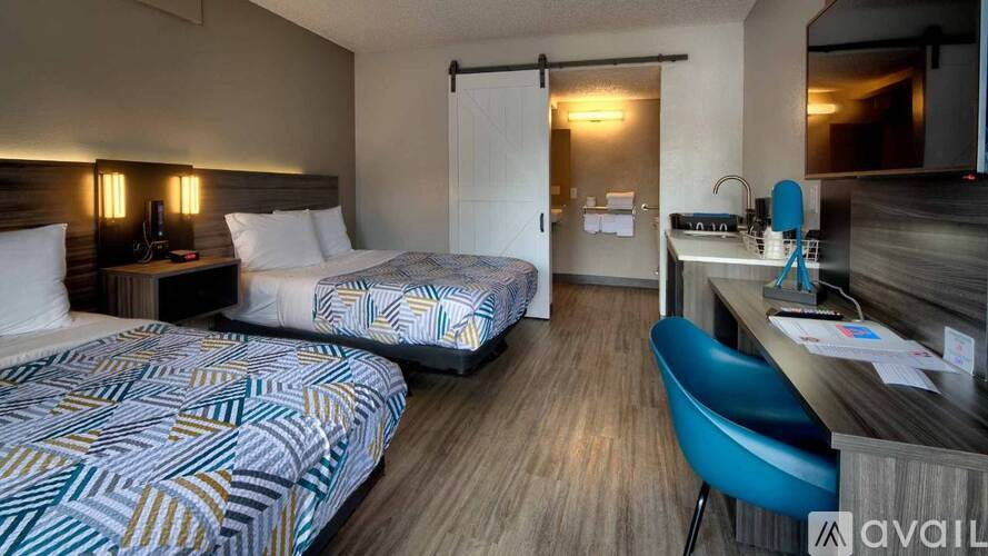 A hotel room with two beds, a desk, and a chair.